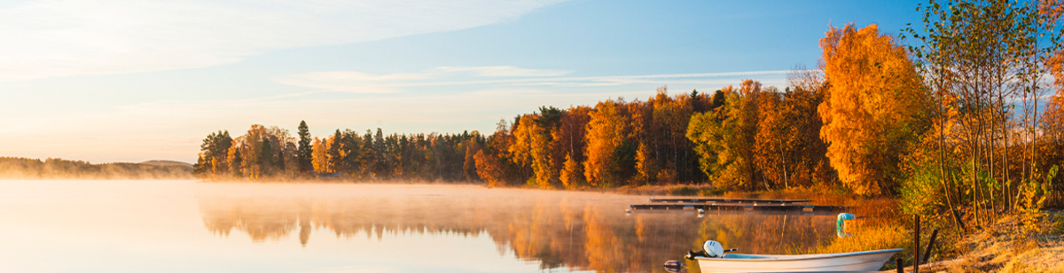 Östergötland. Höstfoto, sjö med träd och båt vid brygga.jpg