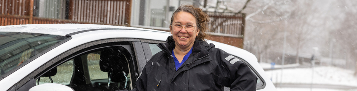 Leende hemtjänstpersonal utanför bil på väg från brukare.