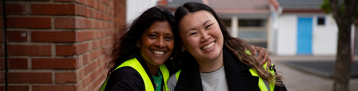 Två fritidspersonal som ler på skolgården.