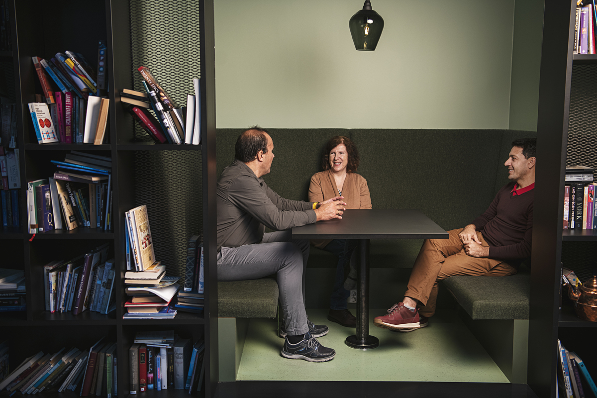 Tre kolleger i samtale sittende i en sofagruppe rundt et firkantet bord.