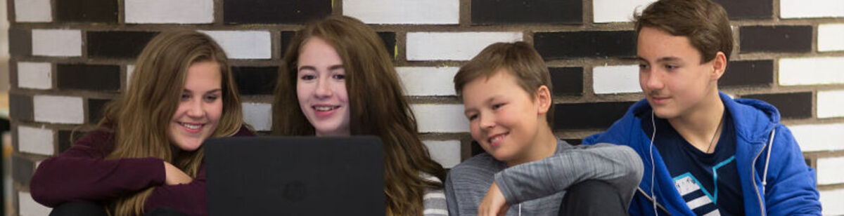 Ungdomar sitter samlade vid en laptop