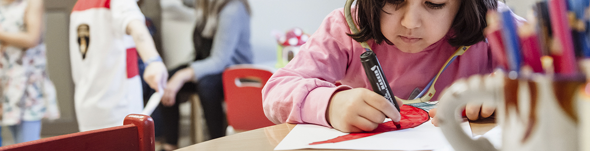 Förskolebarn som målar, andra barn aktiverar sig med annat i bakgrunden