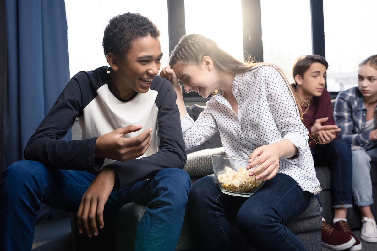21479651-happy-teenagers-sitting-on-sofa-and-eating-popcorn-from.jpg