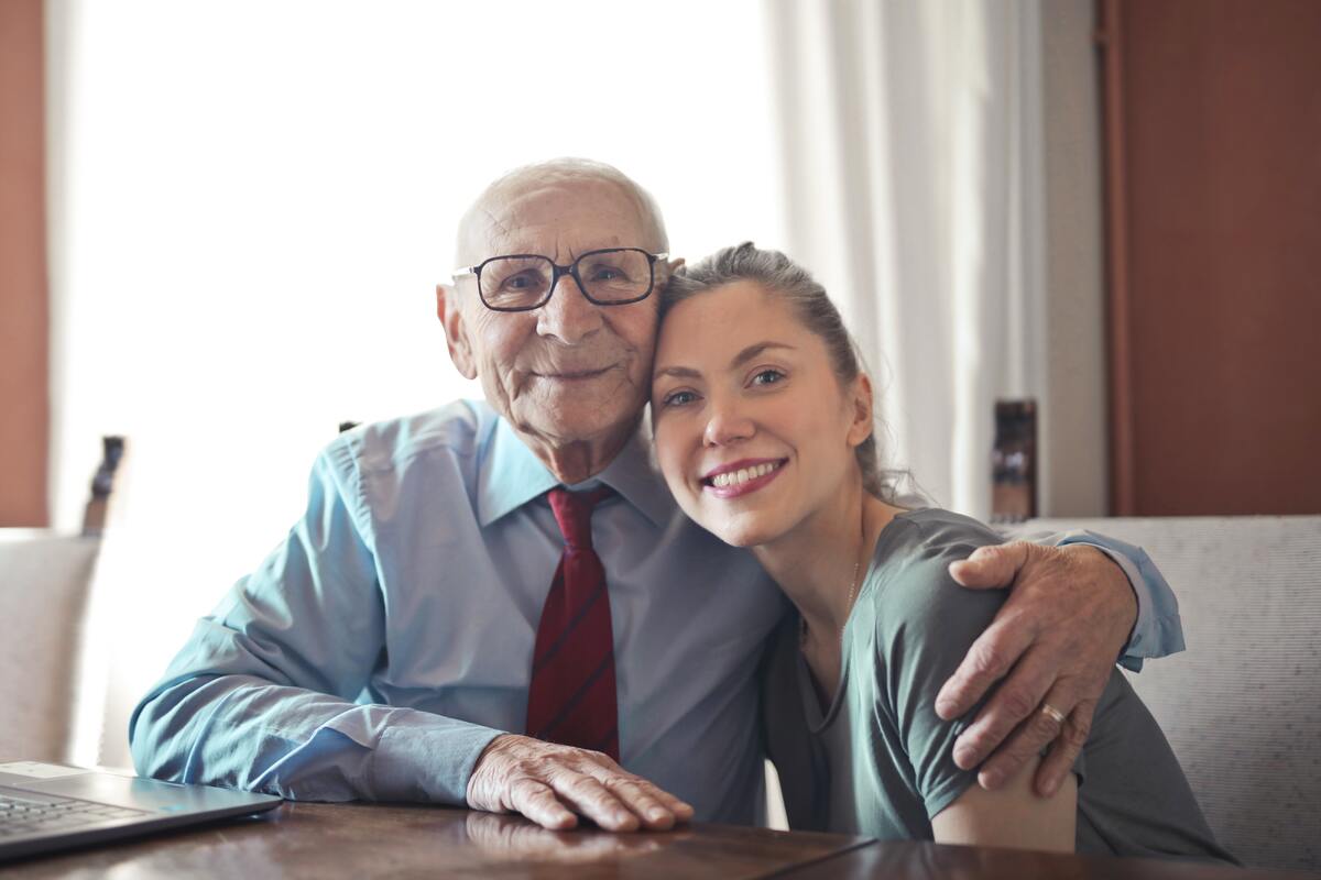 En äldre man som håller armen om en yngre kvinna.