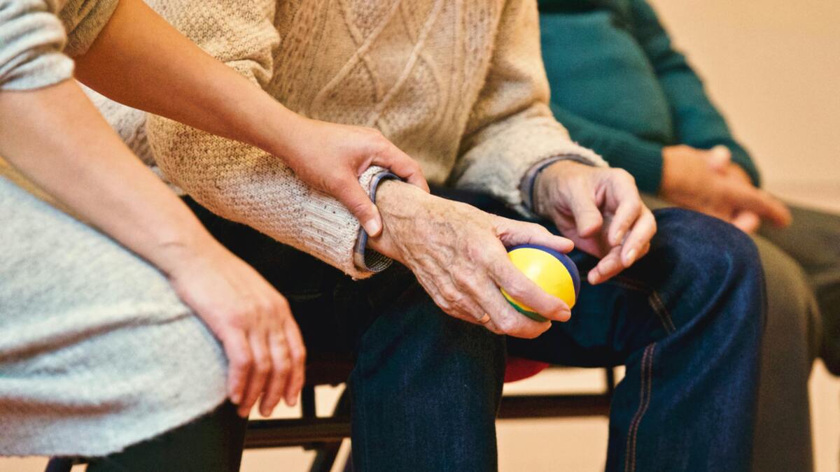 Äldre person sitter med en boll i handen
