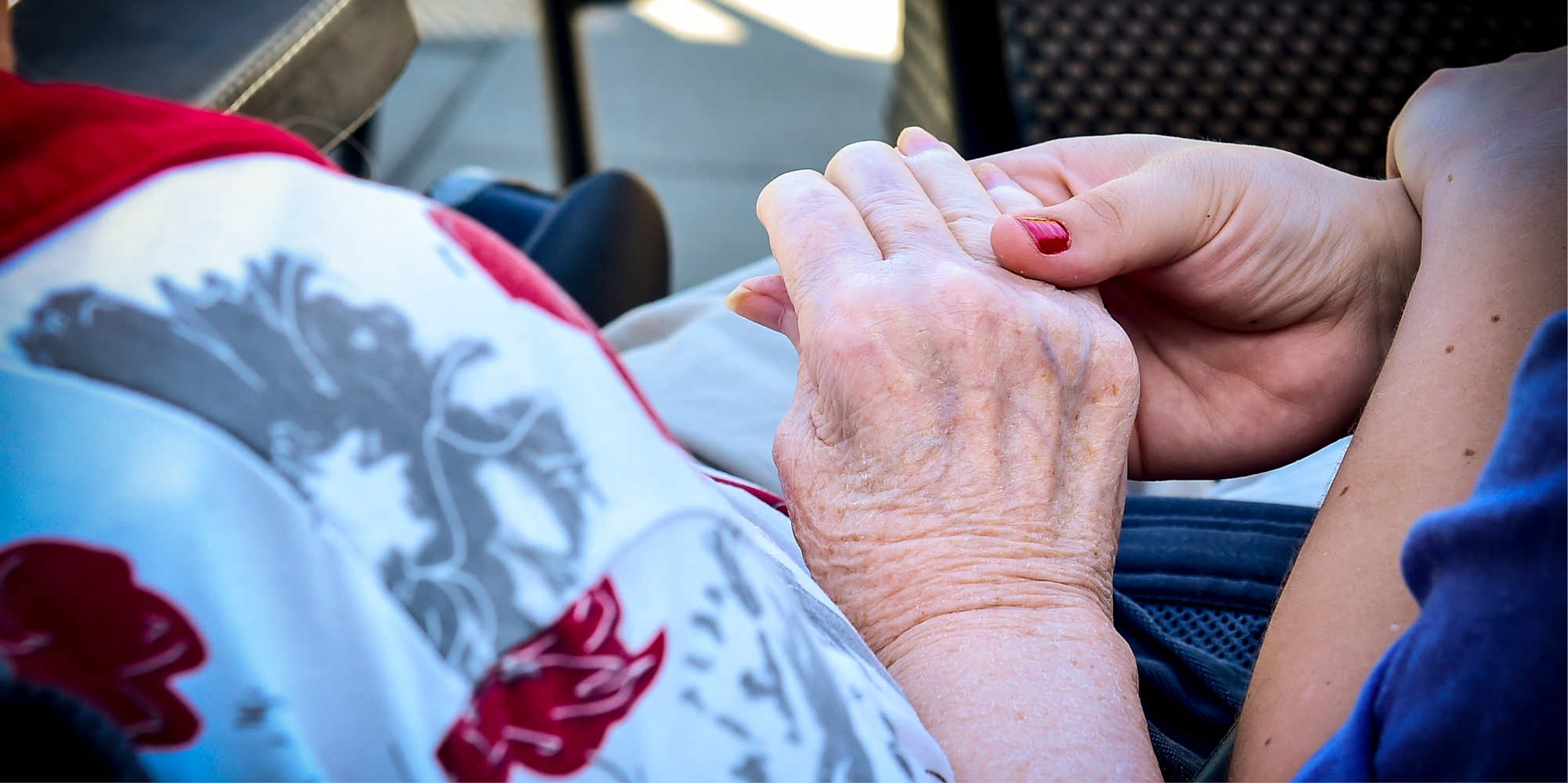 En yngre och äldre person håller i varandras händer. 